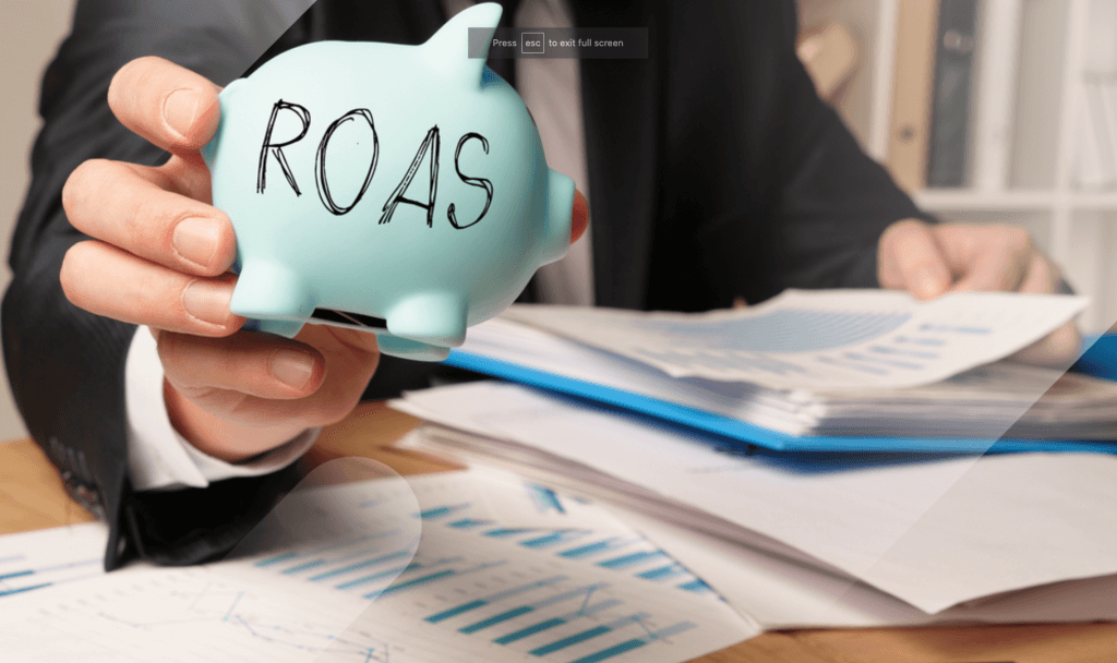ROAS and Ad Spend blog image with man holding piggy bank with ROAS written on it